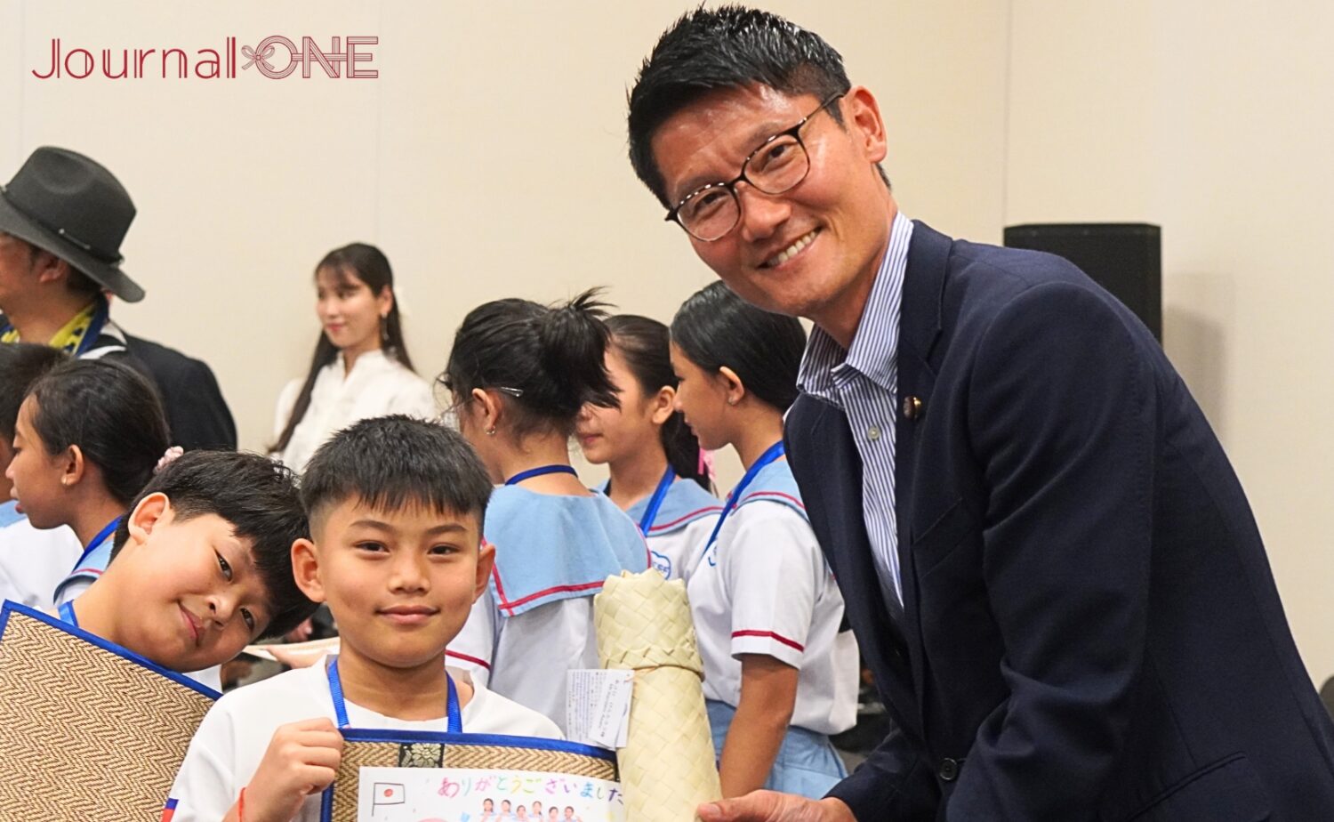 小学生からプレゼントをもらい笑顔の朝日健太郎参議院議員-Journal-ONE撮影