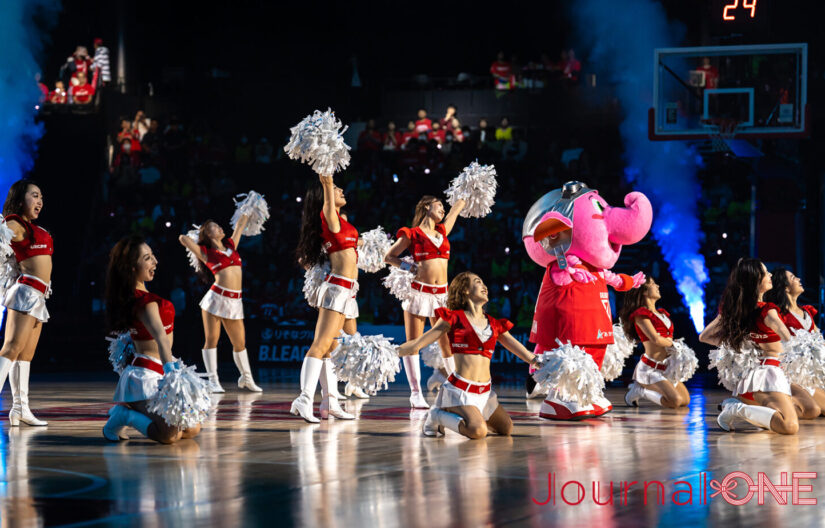 ららアリーナ 東京ベイのコート上で、千葉ジェッツのマスコット「ジャンボくん」とフライトクルーチアリーダー「STAR JETS」が共にパフォーマンスを披露し、会場を盛り上げる様子。