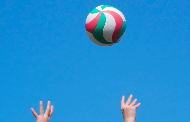 青空を背景にしたバレーボールと選手のシルエット。静岡県沼津市の香陵アリーナで開催されるSVリーグ女子プレーオフ2026のイメージ。