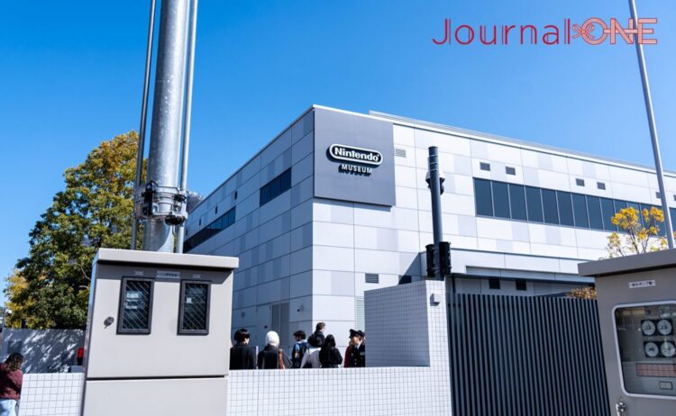 青空の下、京都府宇治市にあるニンテンドーミュージアムの外観。建物には任天堂のロゴマークが掲げられている。