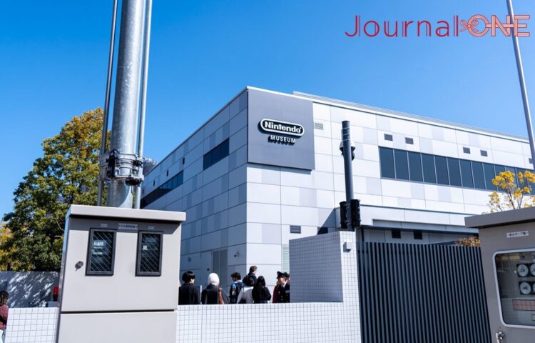 青空の下、京都府宇治市にあるニンテンドーミュージアムの外観。建物には任天堂のロゴマークが掲げられている。