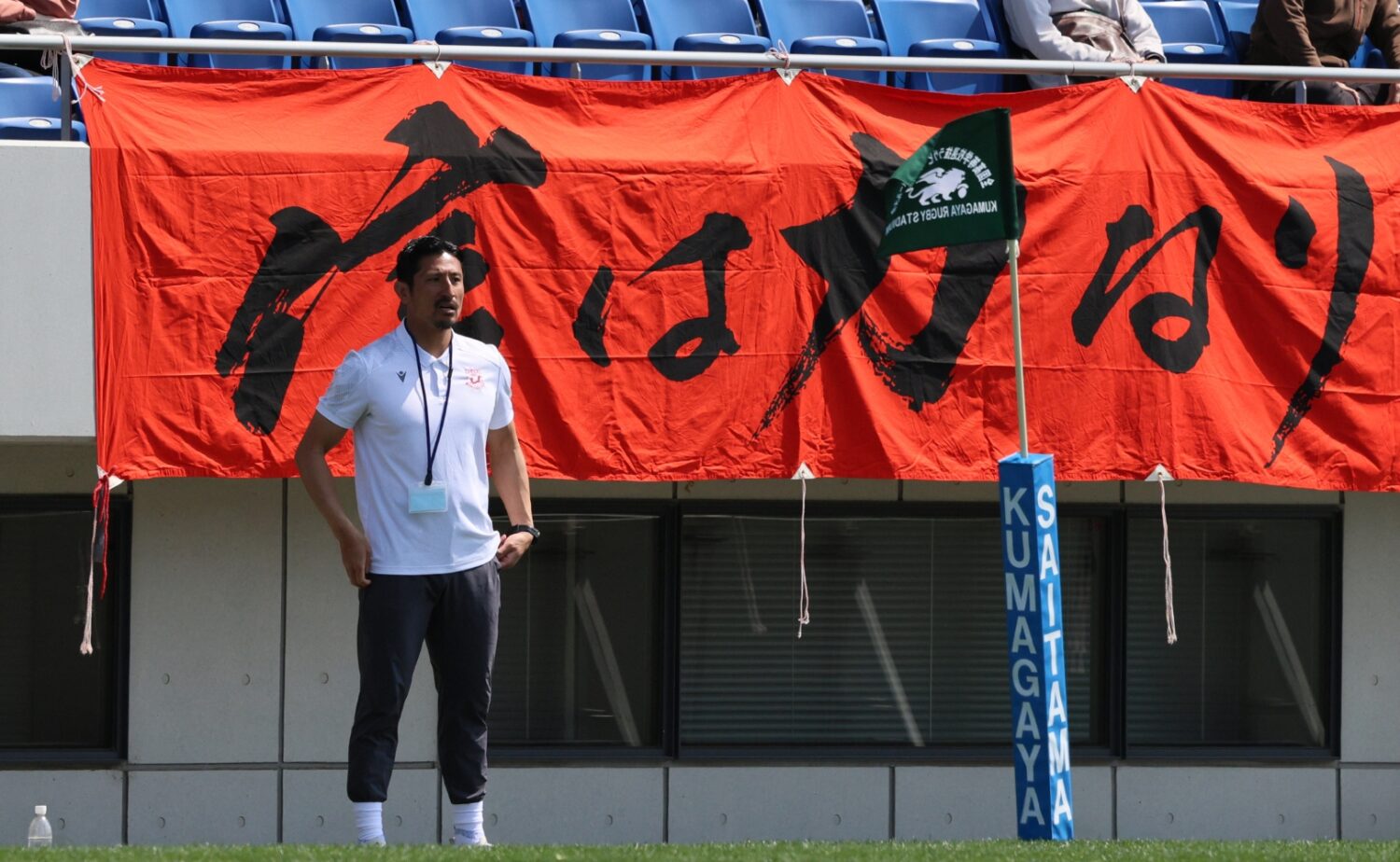 京都工学院のスローガン「信は力なり」の前で戦況を見つめる内田啓介コーチ