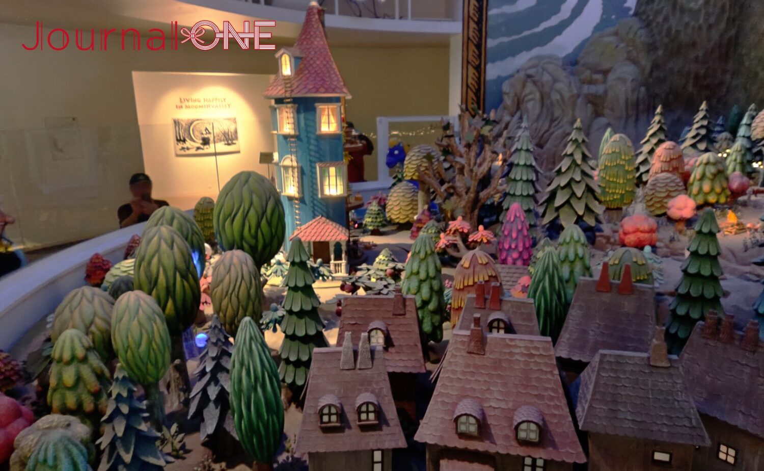 ムーミンバレーパークの展示施設「KOKEMUS（コケムス）」にある、ムーミン谷の巨大ジオラマ。精巧に作られた青いムーミン屋敷と、四季を象徴する多彩な色合いの木々や谷の様子が表現されている。