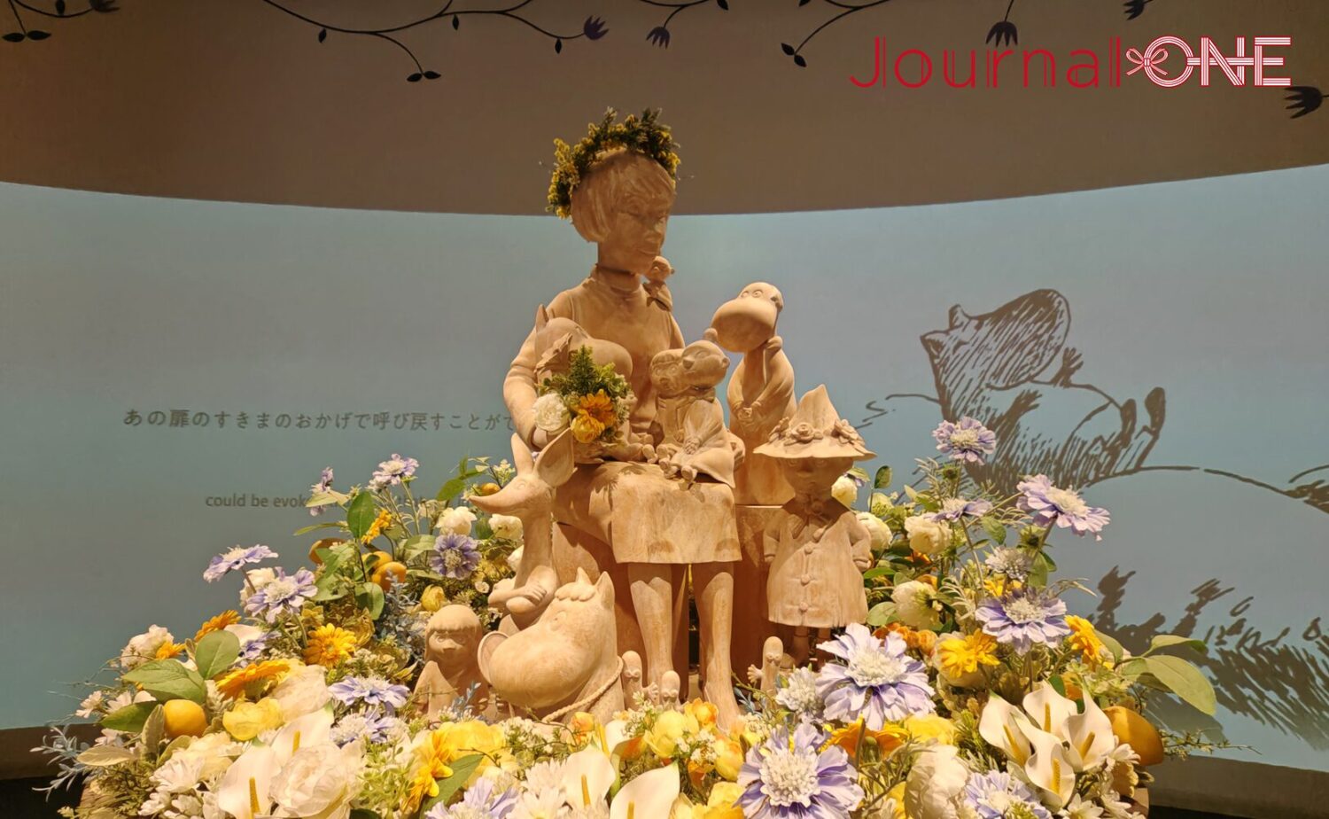 展示施設「KOKEMUS（コケムス）」内にある、原作者トーベ・ヤンソンとムーミン谷のキャラクターたちの木製彫像。周囲は色鮮やかな花々で飾られている。