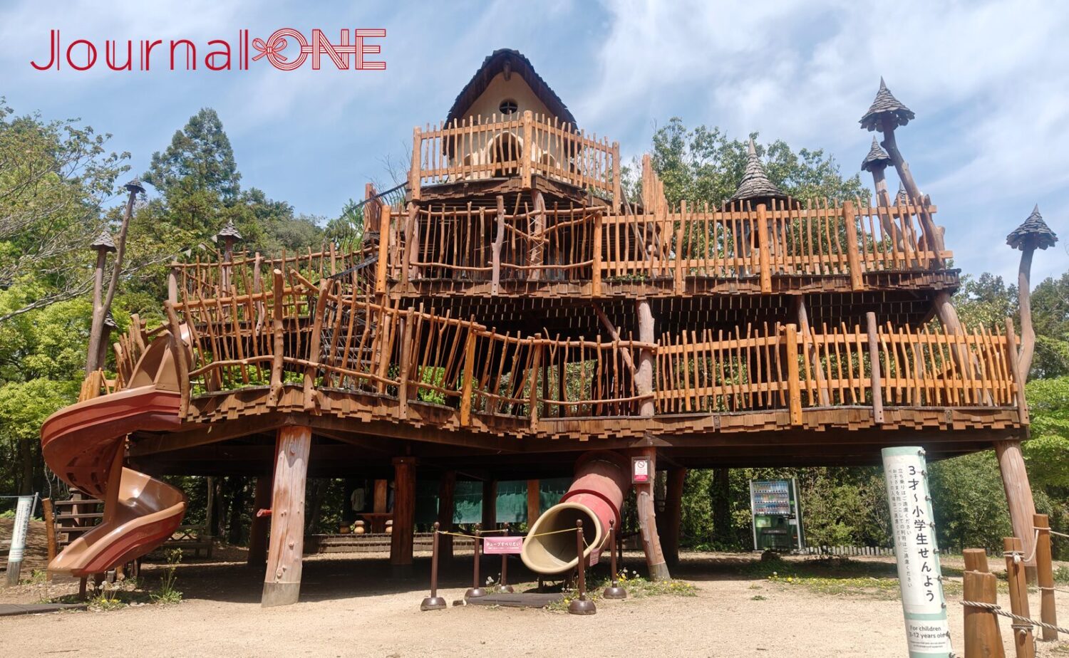 ムーミンバレーパークの「おさびし山」エリアにある「ヘムレンさんの遊園地」。自然の木材を活かした巨大なツリーハウスのようなアスレチック遊具と、滑り台が設置されている様子。