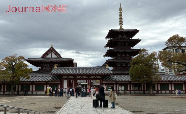 四天王寺の中心伽藍。右側に五重塔、左側に金堂が並び、それらを囲む回廊と入り口の仁王門が見える。手前の開けた広場には参拝客が集まっている。