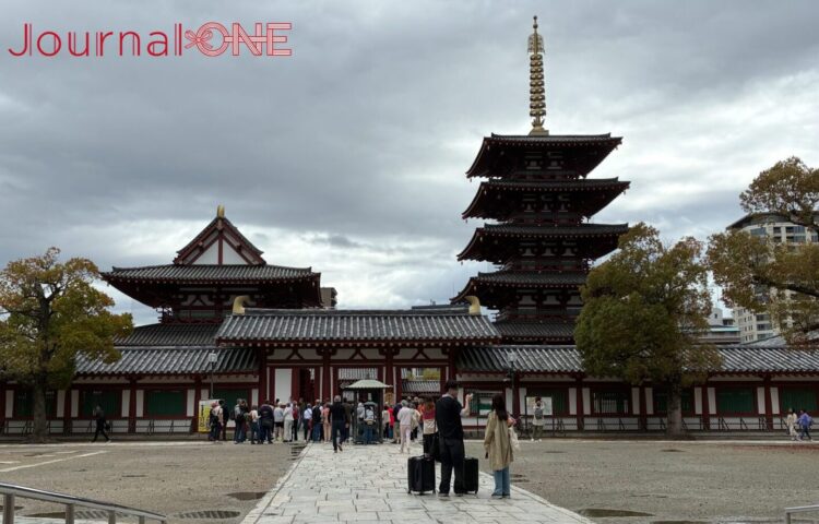四天王寺の中心伽藍。右側に五重塔、左側に金堂が並び、それらを囲む回廊と入り口の仁王門が見える。手前の開けた広場には参拝客が集まっている。